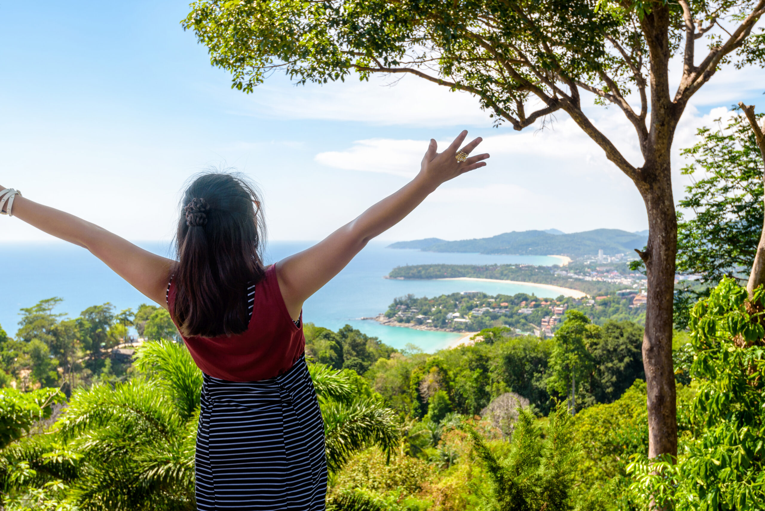 Woman tourist happy gestures on high scenic view for looking beautiful landscape three beach and sea at Hat Kata Karon Viewpoint in Phuket island, Thailand